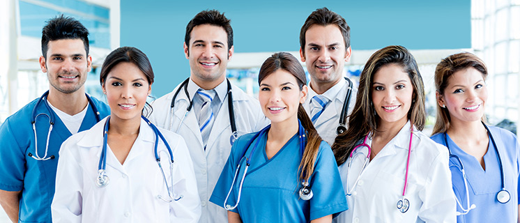 Picture of Physicians and Nurses. There is two male Physicians, two female Physicians, one male Nurse, and two female Nurses. They are all smiling and standing next to each other.